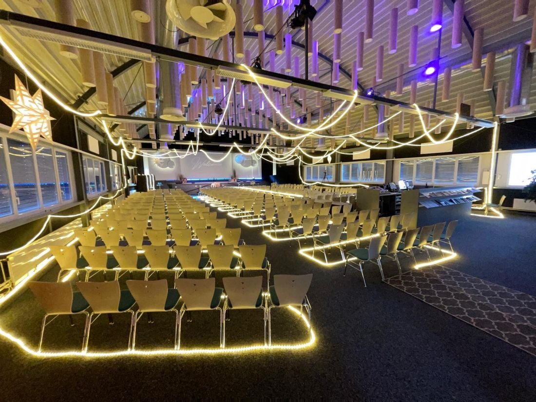 Saal mit Stuhlreihen, die mit Lichtschläuchen eingefasst sind