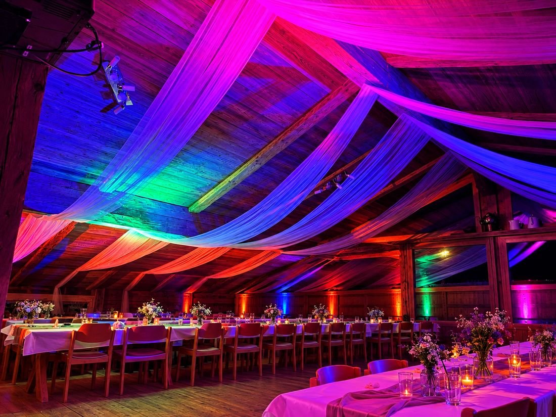Festsaal mit Holzdach, Stoffbahnen und farbigen Uplights